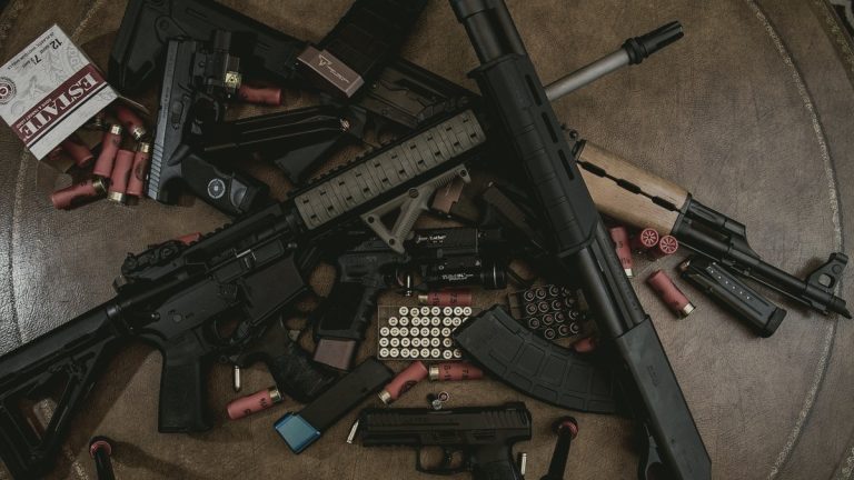 Pump shotgun and shells laid out with other firearms on a table