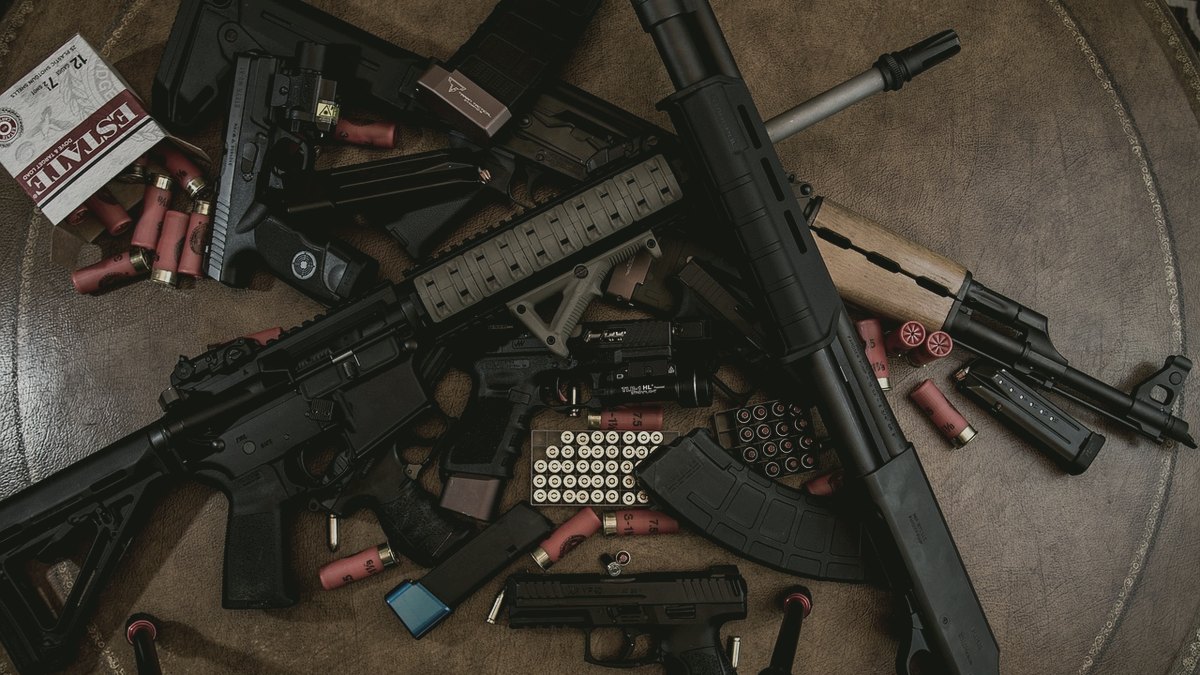 Pump shotgun and shells laid out with other firearms on a table